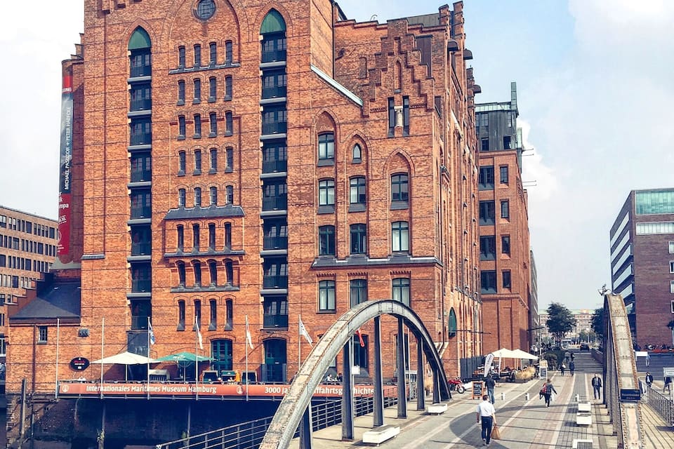 A large red brick building with arched windows and a metal bridge structure in front.