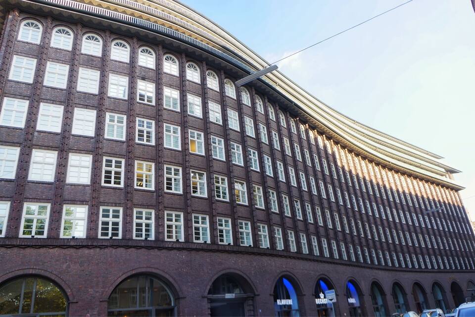 Un grand bâtiment en briques, doté de nombreuses fenêtres et d’entrées en arc de cercle.
