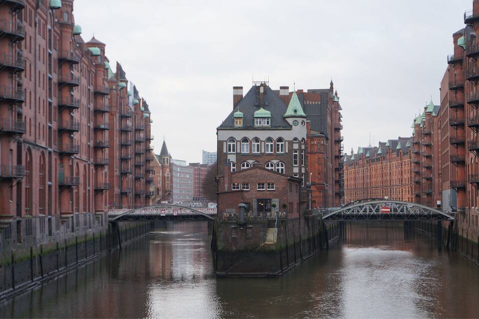 A canal with a bridge and red brick buildings with green roofs.