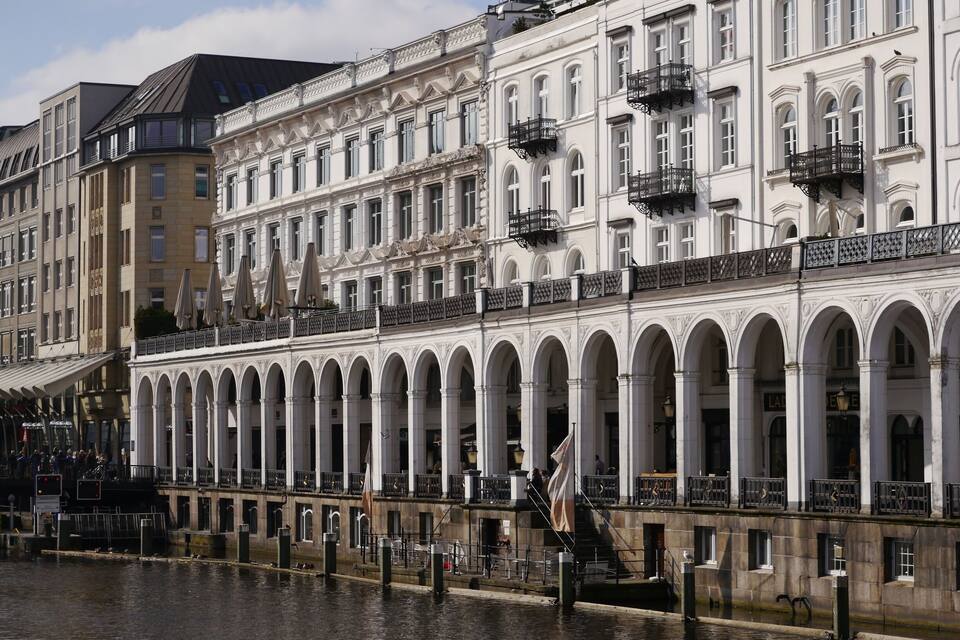 A historic building with arched windows and balconies along a riverside.
