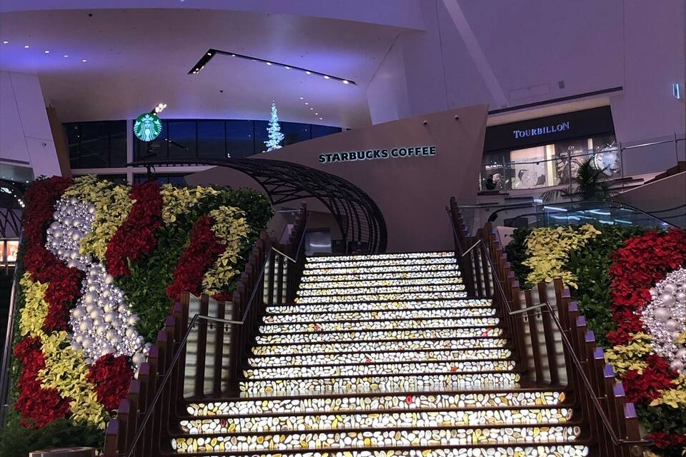 A staircase with illuminated steps and floral decorations, leading to a building labeled "Aria Resort & Casino."