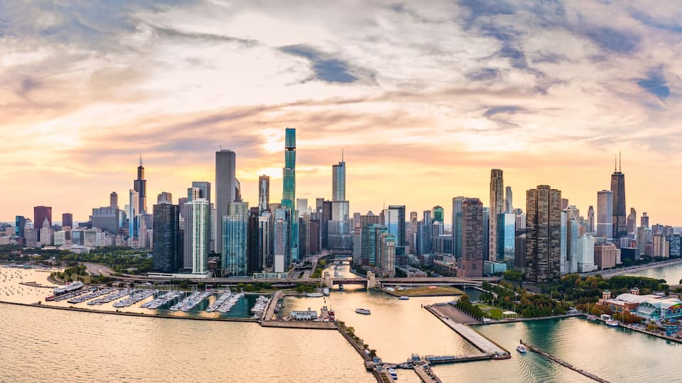 A city skyline with a prominent skyscraper, a marina with boats, and a river.