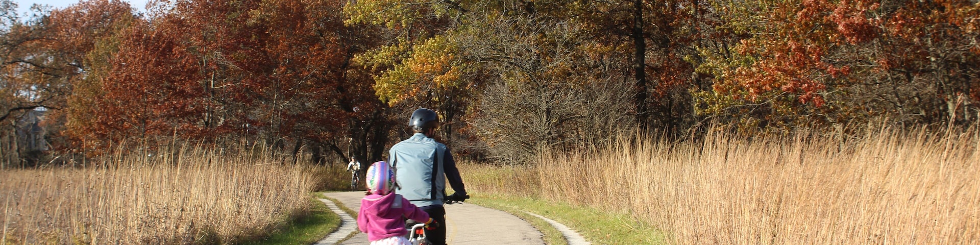 Father and daughter riding bikes on North Branch Trail at Miami Woods in Morton Grove, Illinois in autumn