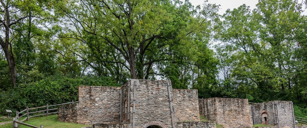 A stone fort with arched gateways and a wooden fence.