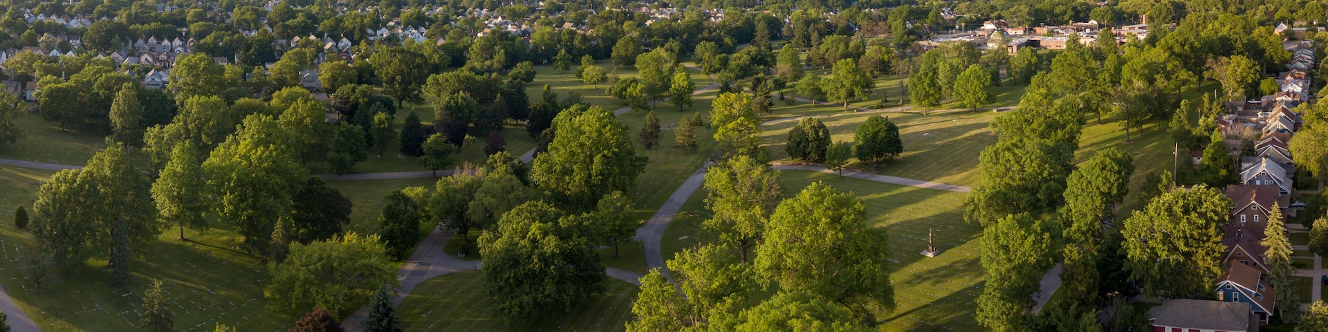 A residential area with houses, trees, and a cemetery.