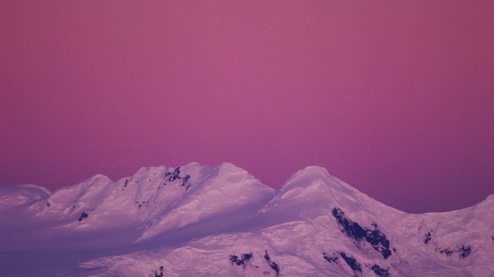 A moonlit mountain range under a purple sky.