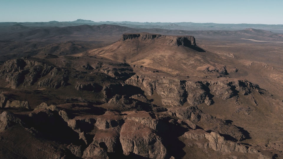 A rugged mountainous landscape with prominent rocky formations and a flat-topped hill in the center.