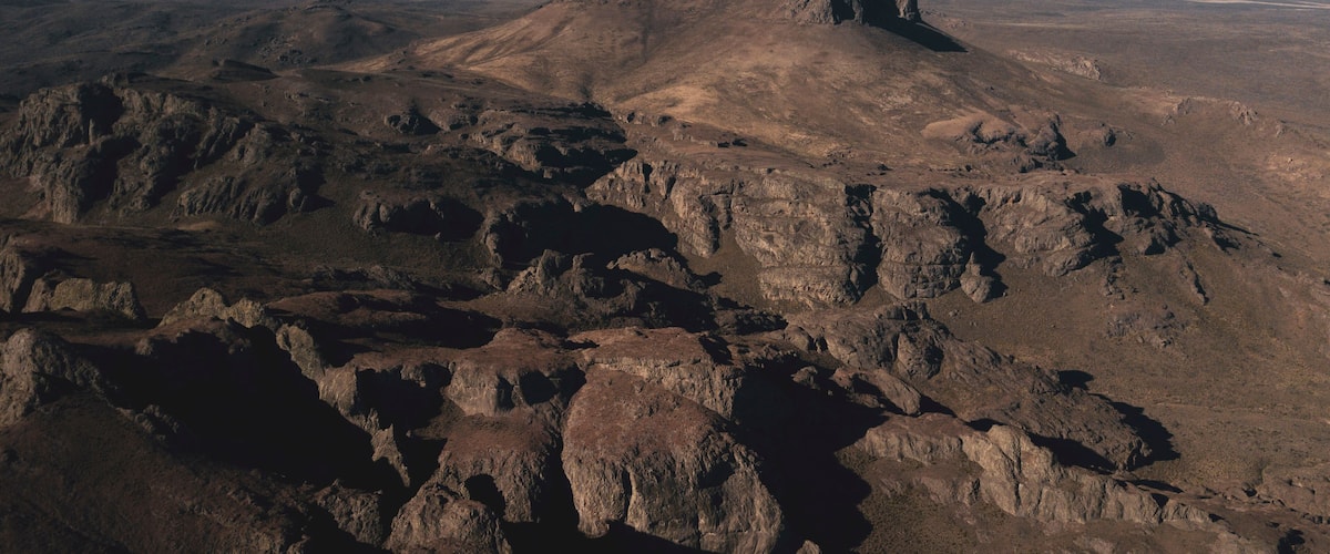 A rugged mountainous landscape with prominent rocky formations and a flat-topped hill in the center.