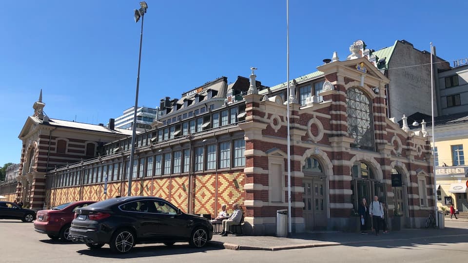 Un edificio histórico con intrincados detalles de ladrillo y una alta torre con reloj.