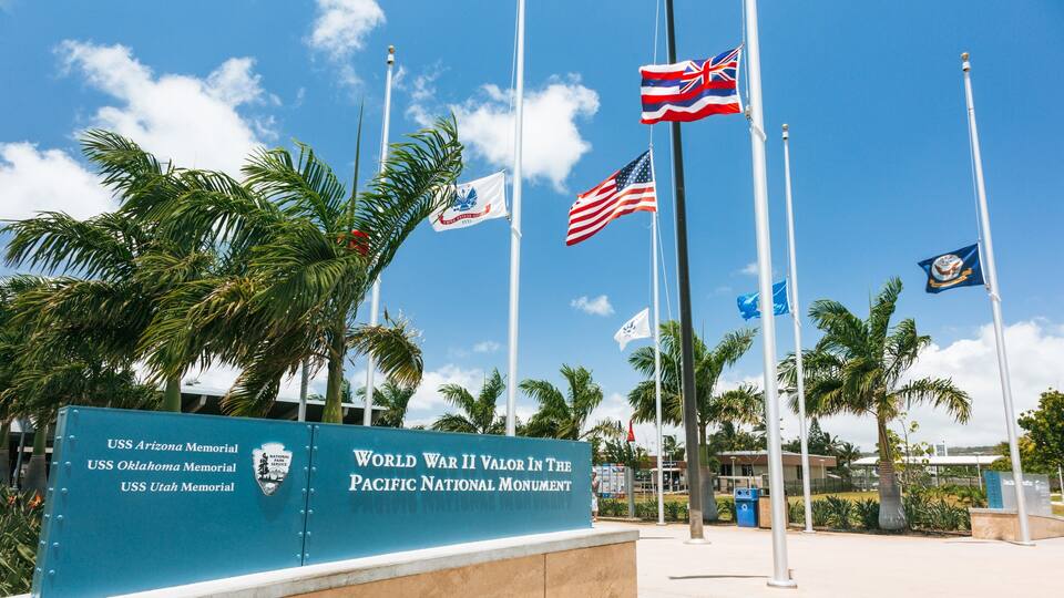 The USS Arizona Memorial with flags of the USA, UK, and others.