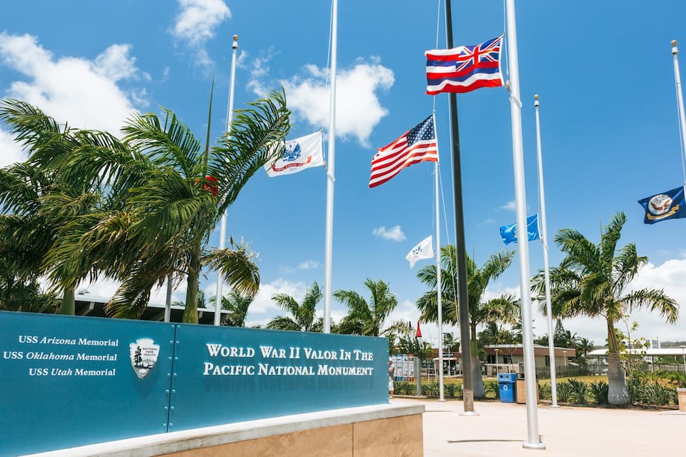 The USS Arizona Memorial with flags of the USA, UK, and others.
