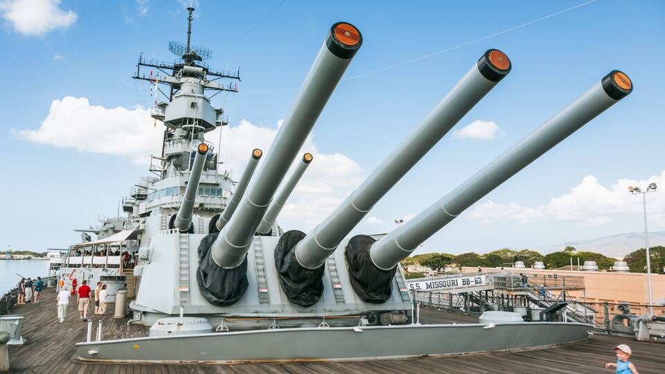 A large naval ship with multiple gun turrets and a bridge structure.
