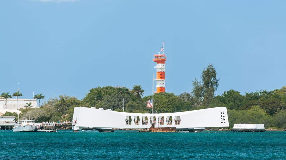 A white ship with a flag, a lighthouse, and palm trees.