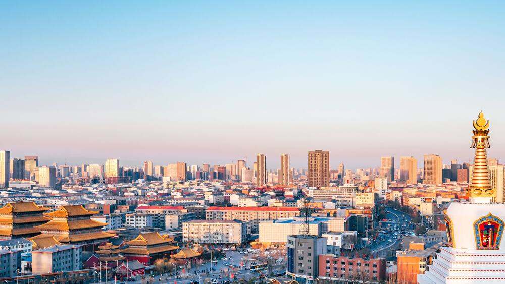 A cityscape with traditional architecture and a prominent golden stupa.