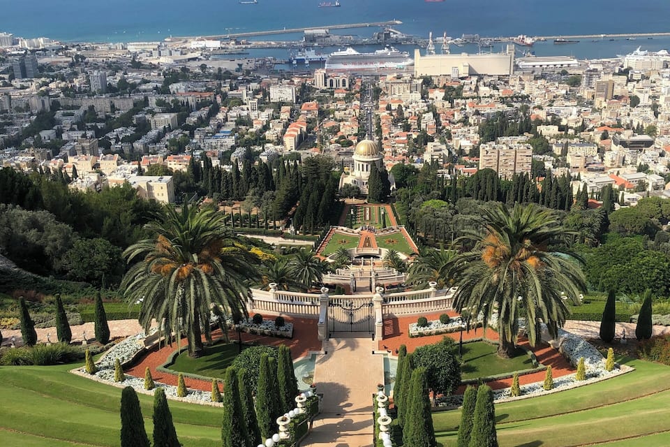 Un paisatge urbà amb una cúpula destacada, envoltat de jardins exuberants i palmeres.
