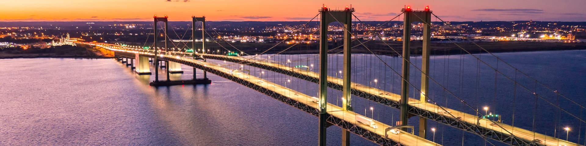 Aerial view of Delaware Memorial Bridge at dusk. The Delaware Memorial Bridge is a set of twin suspension bridges crossing the Delaware River between the states of Delaware and New Jersey