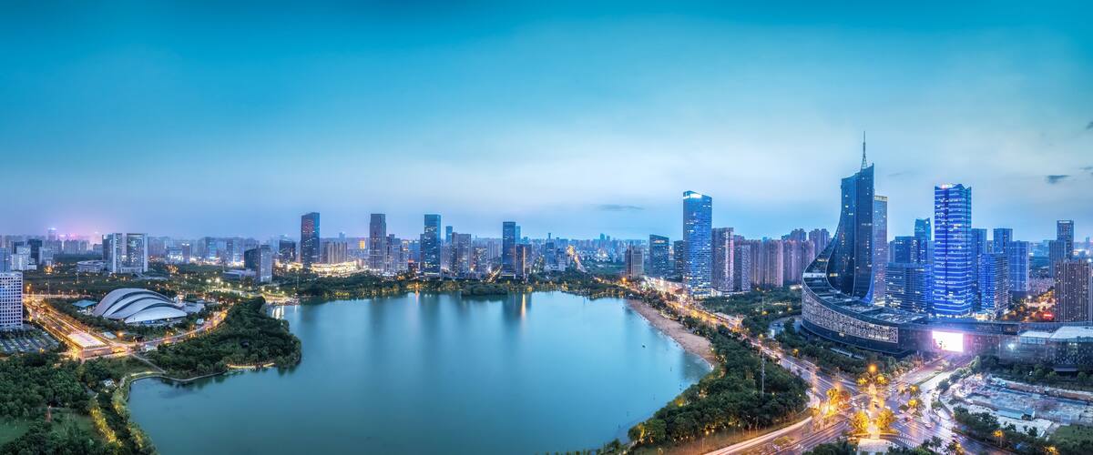 A cityscape with a large body of water, high-rise buildings, and a curved structure near the water's edge.