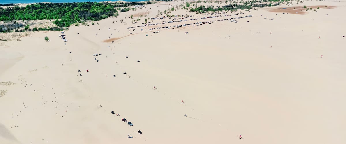 A vast sandy beach with scattered vehicles and sparse vegetation.