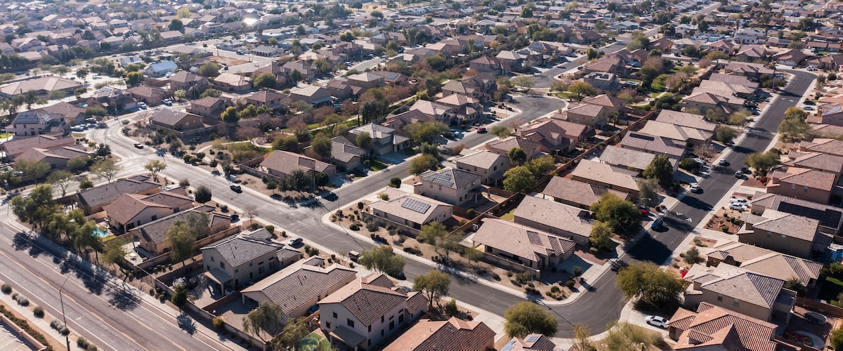 A suburban neighborhood with uniform houses, clear roads, and distant mountains.