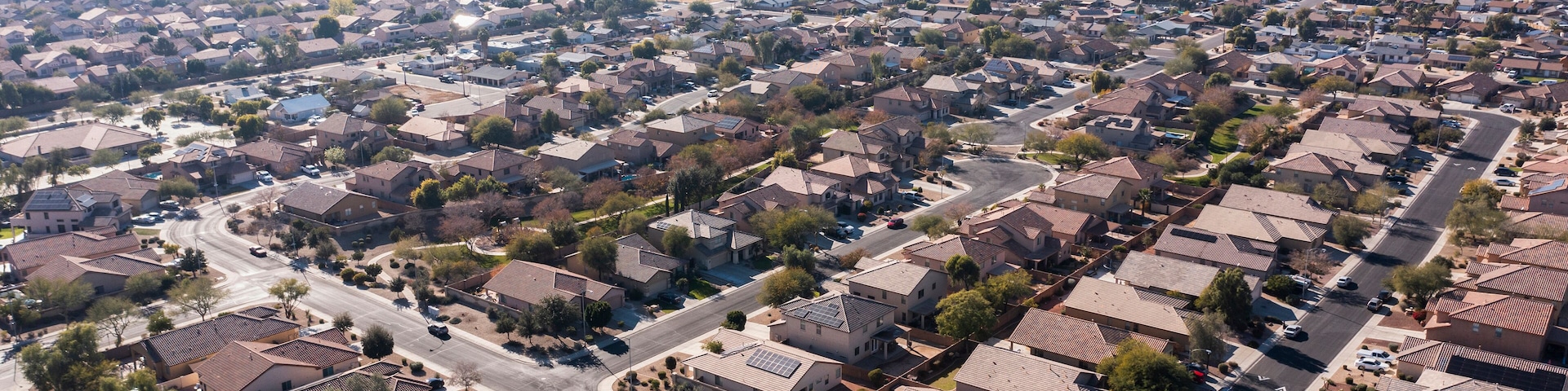 A suburban neighborhood with uniform houses, clear roads, and distant mountains.