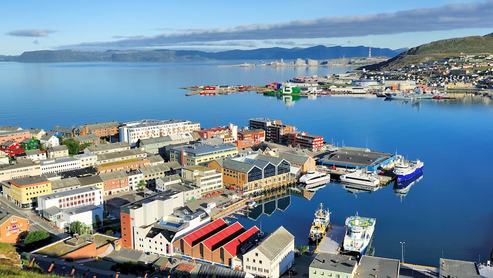 A harbor with boats, buildings, and a distant lighthouse.