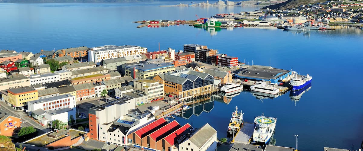 A harbor with boats, buildings, and a distant lighthouse.