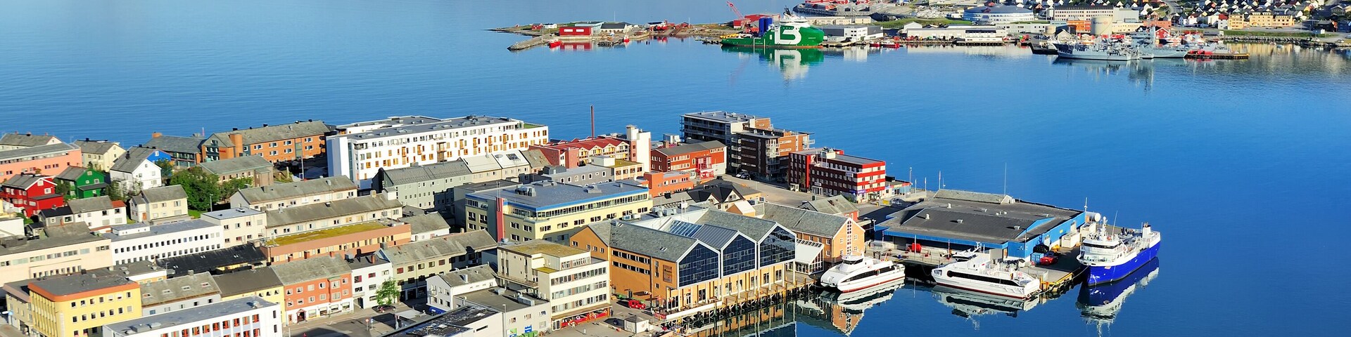 Un puerto con barcos, edificios y un faro distante.