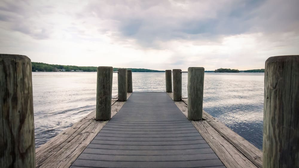 A wooden pier extending into calm water with a cloudy sky above.