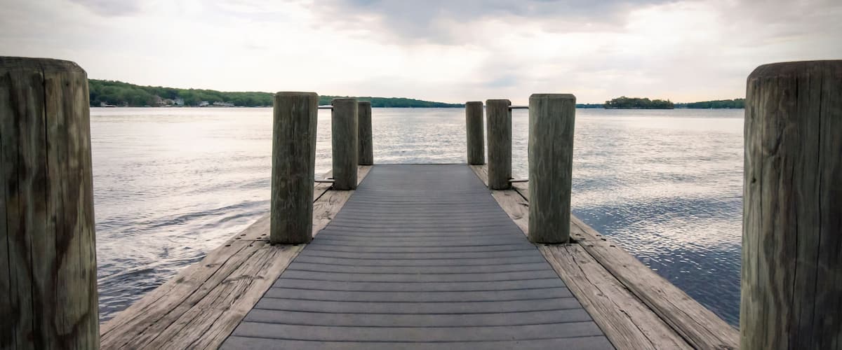 Un muelle de madera que se adentra en aguas tranquilas bajo un cielo nublado.