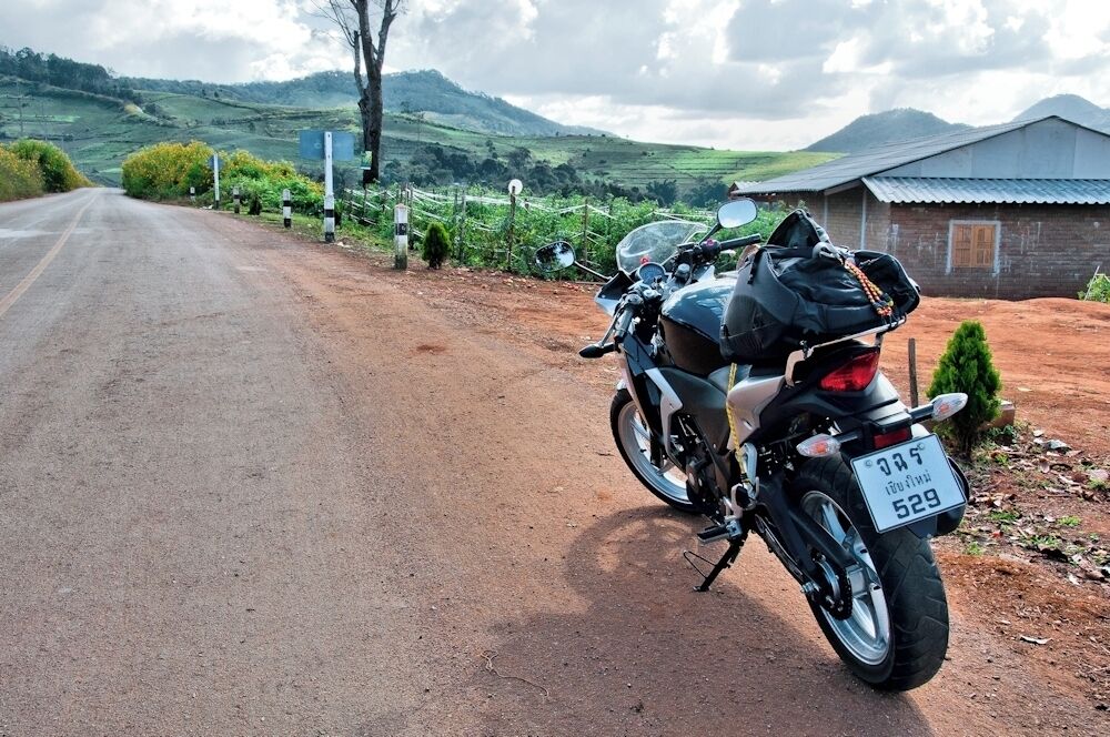 A motorcycle parked on a rural road with a scenic landscape in the background.