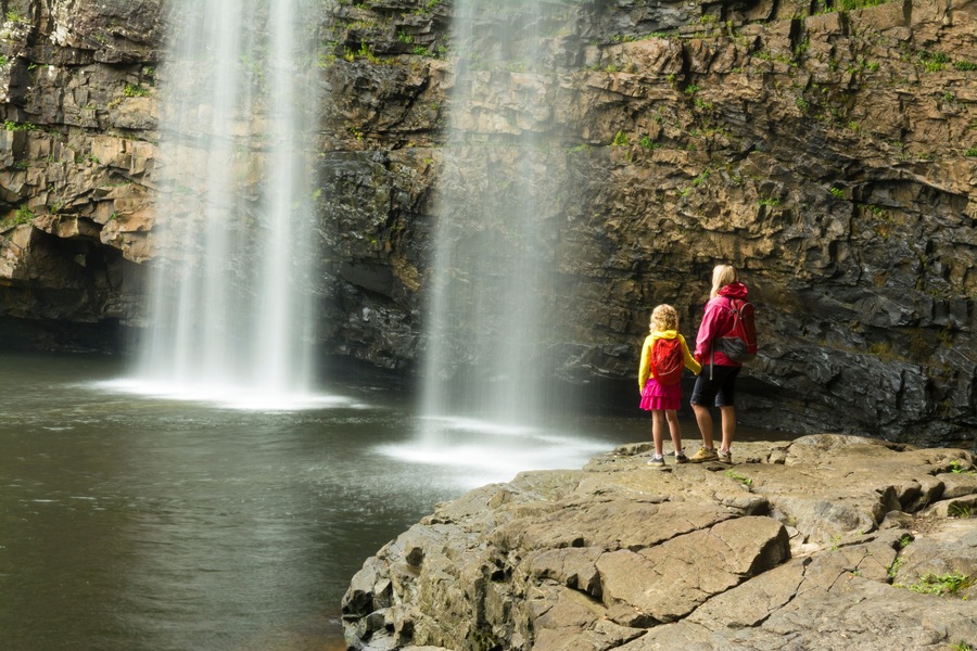 A woman and daughter hikiing below waterfall in Fall Creek Falls State Park, Pikeville, Tennesee.
