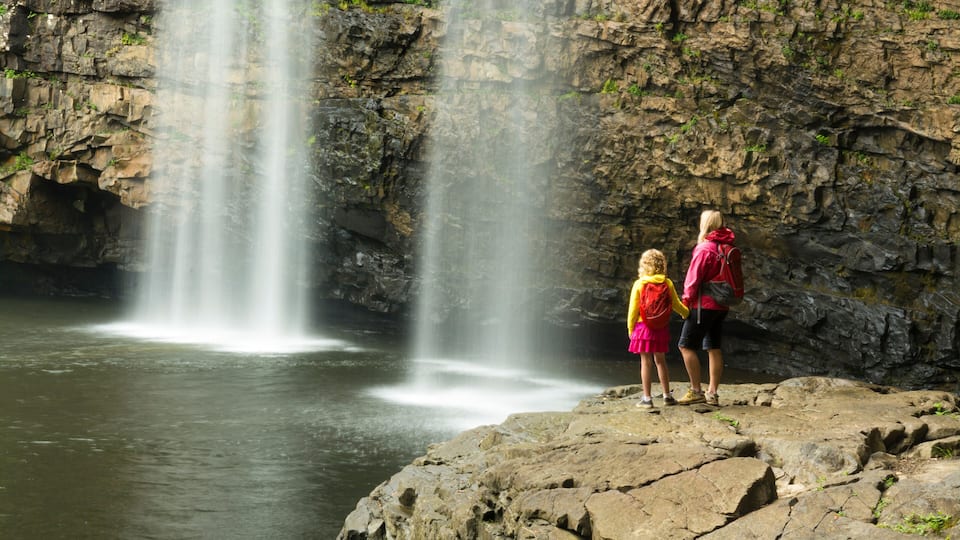 A woman and daughter hikiing below waterfall in Fall Creek Falls State Park, Pikeville, Tennesee.