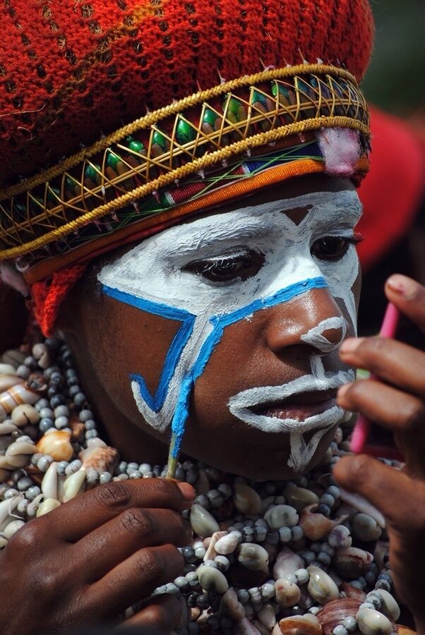 Imagine trying to put on your makeup with such a tiny mirror!

The annual Sing-Sing in Mt. Hagen attracts 50-100 tribes from the  highlands. They arrive early morning and spend a couple hours putting on makeup, creating their head dresses (from stratch, on the day), and gladly posing for pictures before the show starts in the afternoon. Upon entering the Sing-Sing, they will play drums, chant their tribes songs and parade around the grounds. 
The intricate head dresses, tribal jewellery and colorful costumes show how talented they really are.
The Sing-Sing is usually every August. Tickets and hotel accommodation well in advance.
If you are travelling to PNG this is a must!