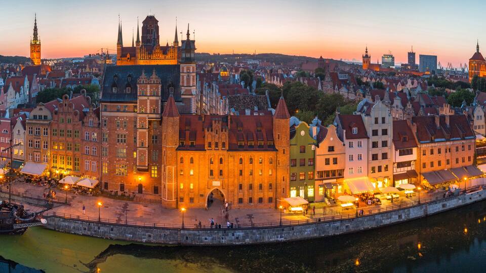 A panoramic view of a historic European city with a prominent cathedral, a river, and a waterfront promenade.
