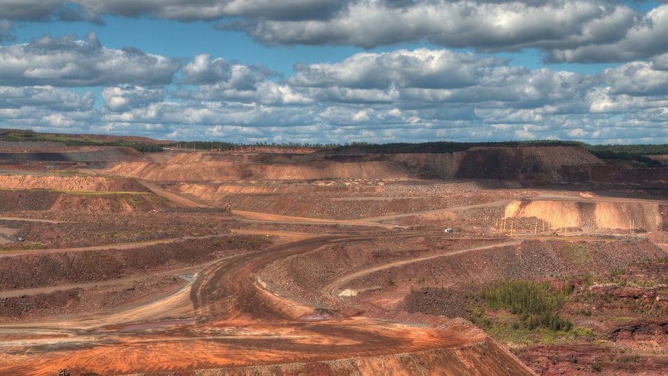 A large open-pit mine with winding roads and a distant horizon.