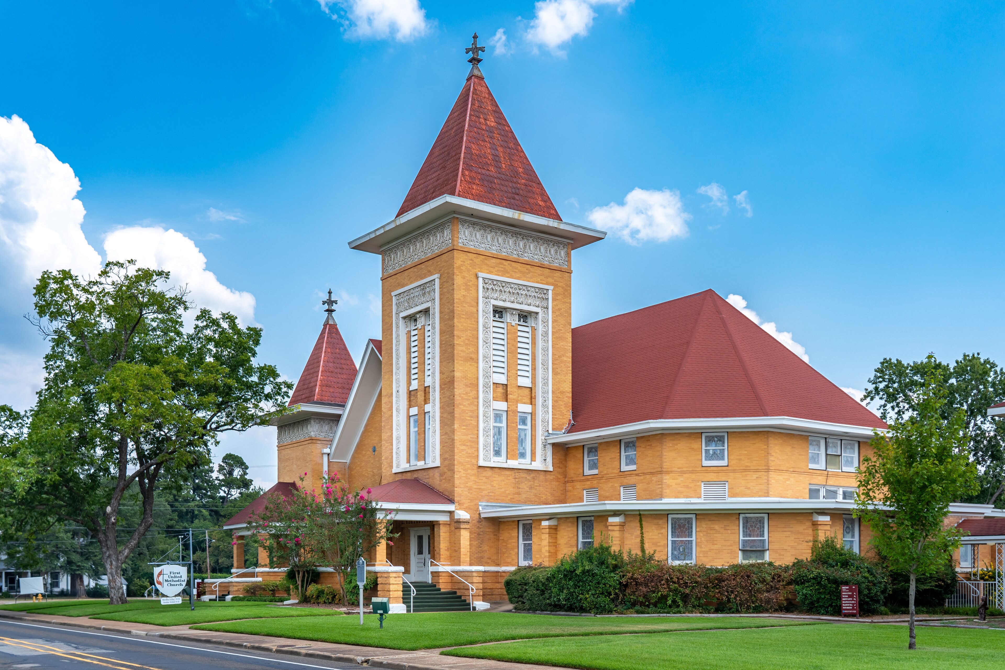 A large yellow church with a red roof and a tower.
