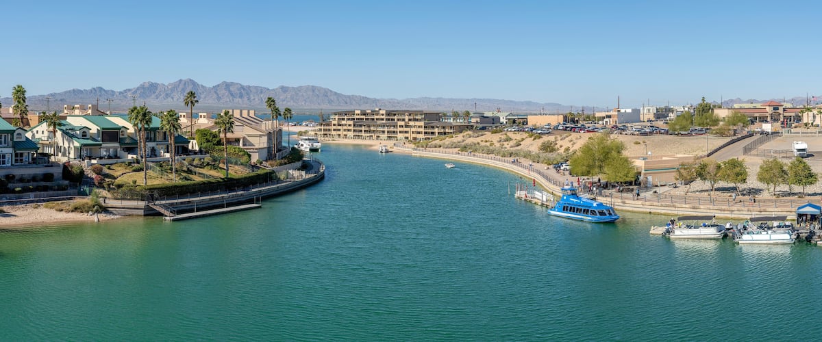 A coastal town with a marina, boats, and a mountainous backdrop.