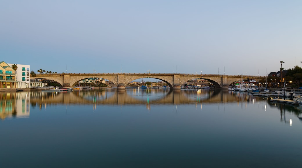 Un pont de pierre enjambant une étendue d’eau calme, où se reflètent les bateaux et les bâtiments.