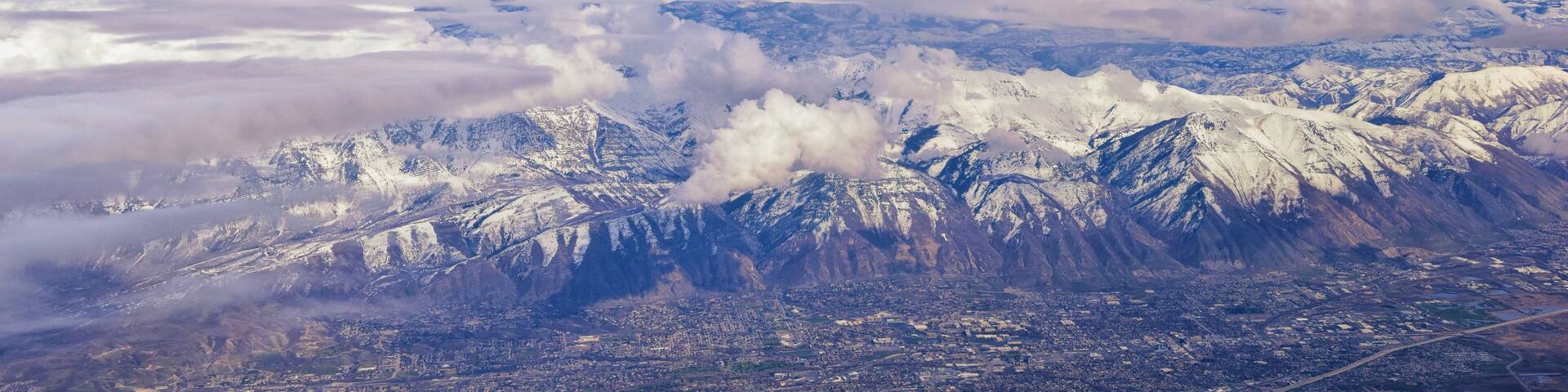 Aerial view from airplane of the Wasatch Front Rocky Mountain Range with snow capped peaks in winter including urban cities of Provo, Farmington Bountiful, Orem and Salt Lake City. Utah. United States