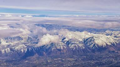 Aerial view from airplane of the Wasatch Front Rocky Mountain Range with snow capped peaks in winter including urban cities of Provo, Farmington Bountiful, Orem and Salt Lake City. Utah. United States