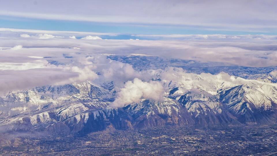 A mountainous landscape with snow-covered peaks and a city below.