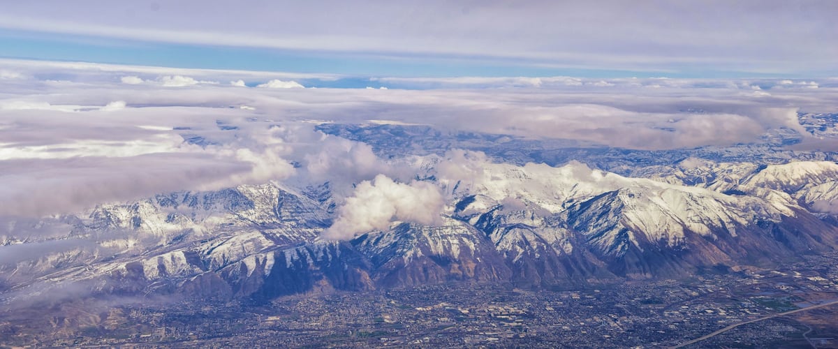 A mountainous landscape with snow-covered peaks and a city below.