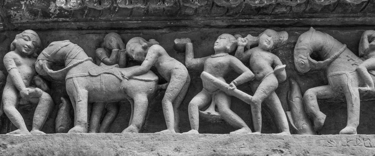 A stone relief depicting a procession of figures, some seated and some standing, in a historical or religious context.