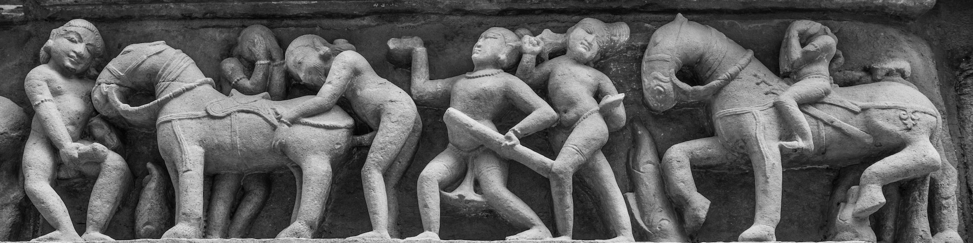 A stone relief depicting a procession of figures, some seated and some standing, in a historical or religious context.