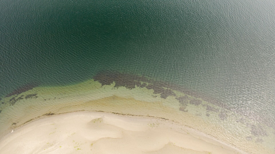 A beach with clear water and a sandy shore.