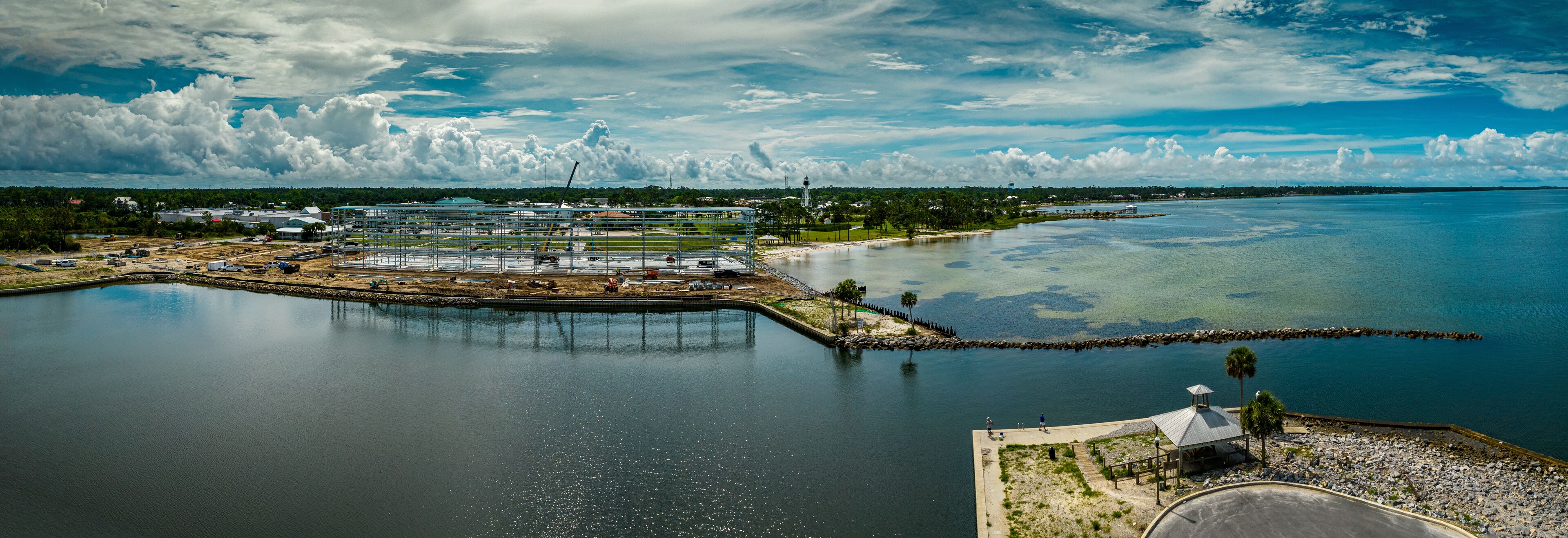 A coastal industrial area with a large body of water, a dock, and a small island with a gazebo.
