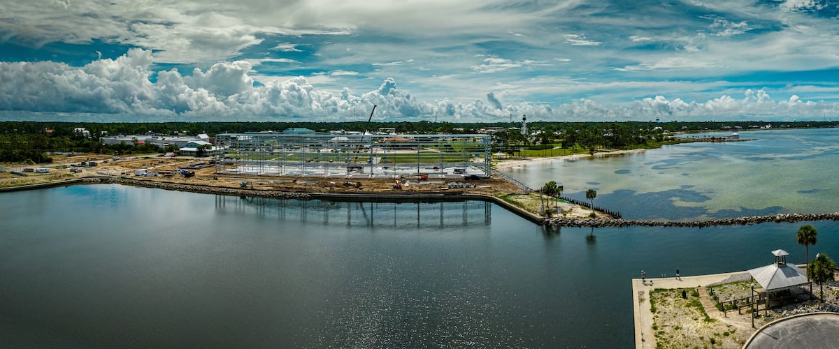 A coastal industrial area with a large body of water, a dock, and a small island with a gazebo.
