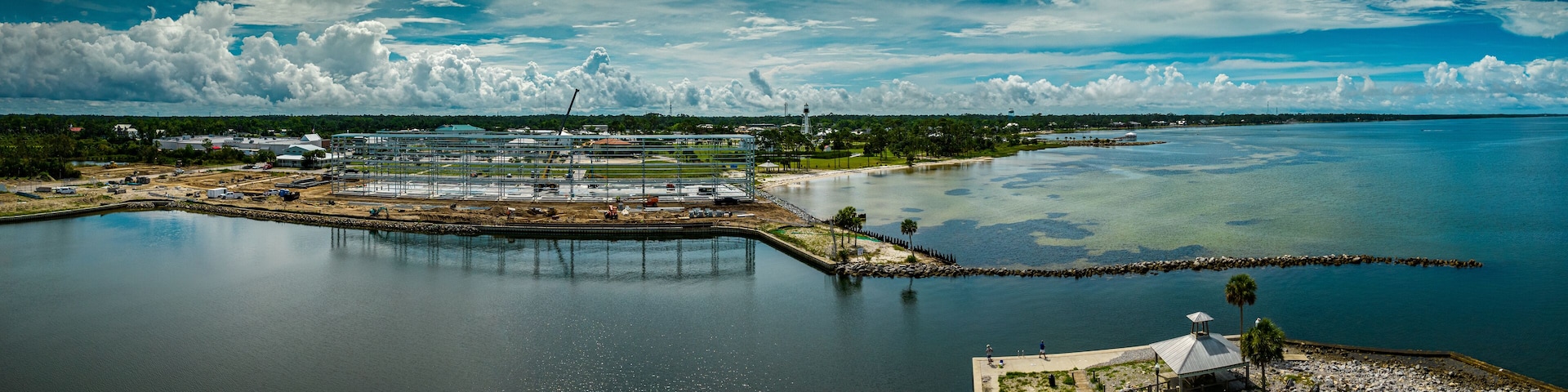 A coastal industrial area with a large body of water, a dock, and a small island with a gazebo.