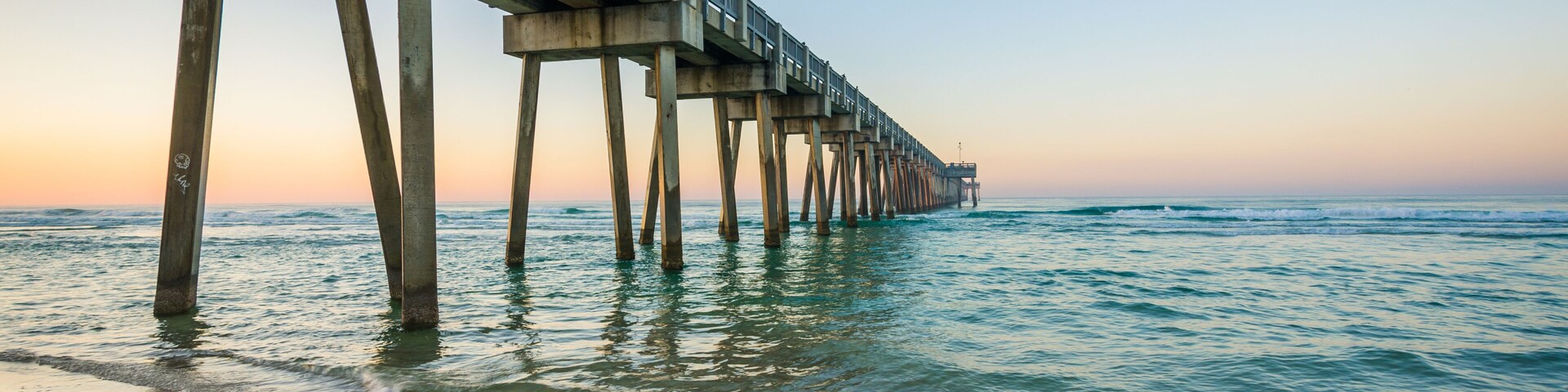 Un muelle se adentra en el océano bajo cielos despejados.