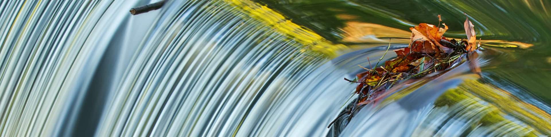 Portage Creek Cascade captured with motion blur and illuminated by reflected color from sunlit autumn trees at sunrise, Milham Park, Michigan, USA